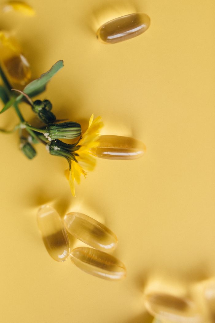 services-03 Yellow softgels and dandelion flower on a vibrant yellow surface, representing natural supplements.